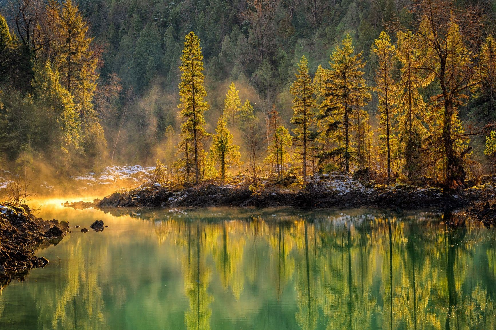 <p>Misty morning light filters through golden-hued trees, casting shimmering reflections on tranquil waters in Anhluut'ukwsim Lax̱mihl Angwinga'asanskwhl Nisg̱a'a Park. Courtesy of Destination BC</p>